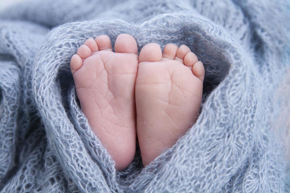 Baby feet wrapped in a blue knitted blanket